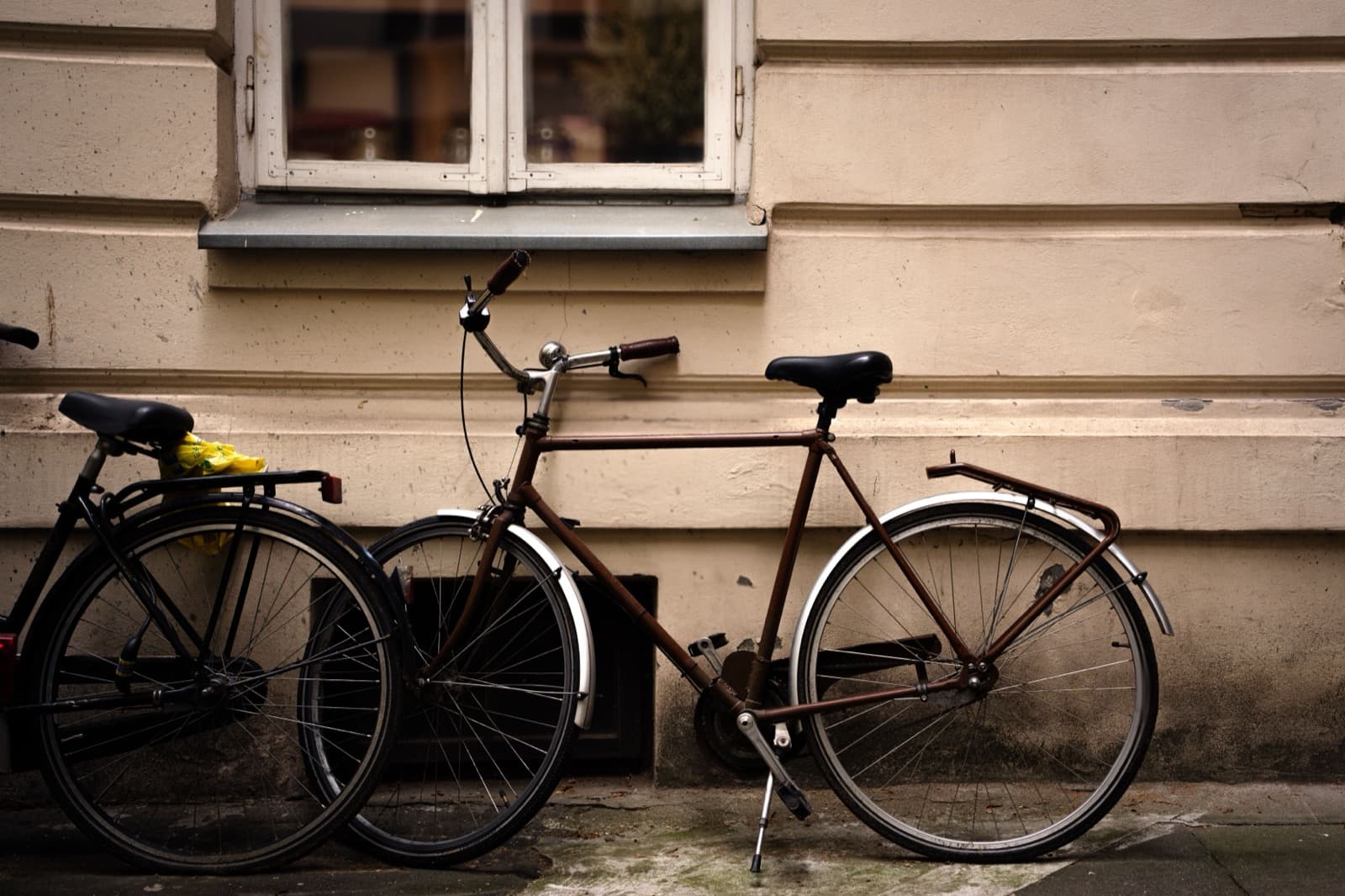 Bicycles parked against a building wall on a city street