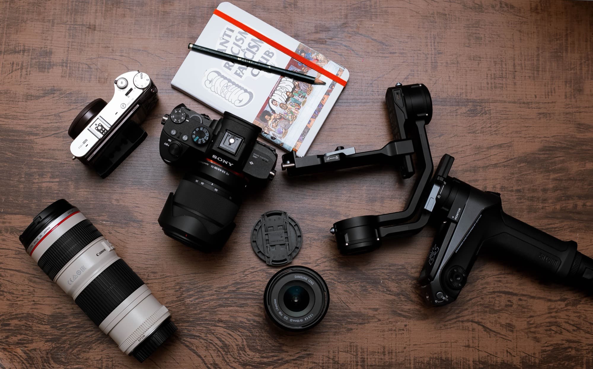 Camera, lenses, gimbal and notes scattered across a desk, representing the scattered tools rental businesses juggle without a connected system