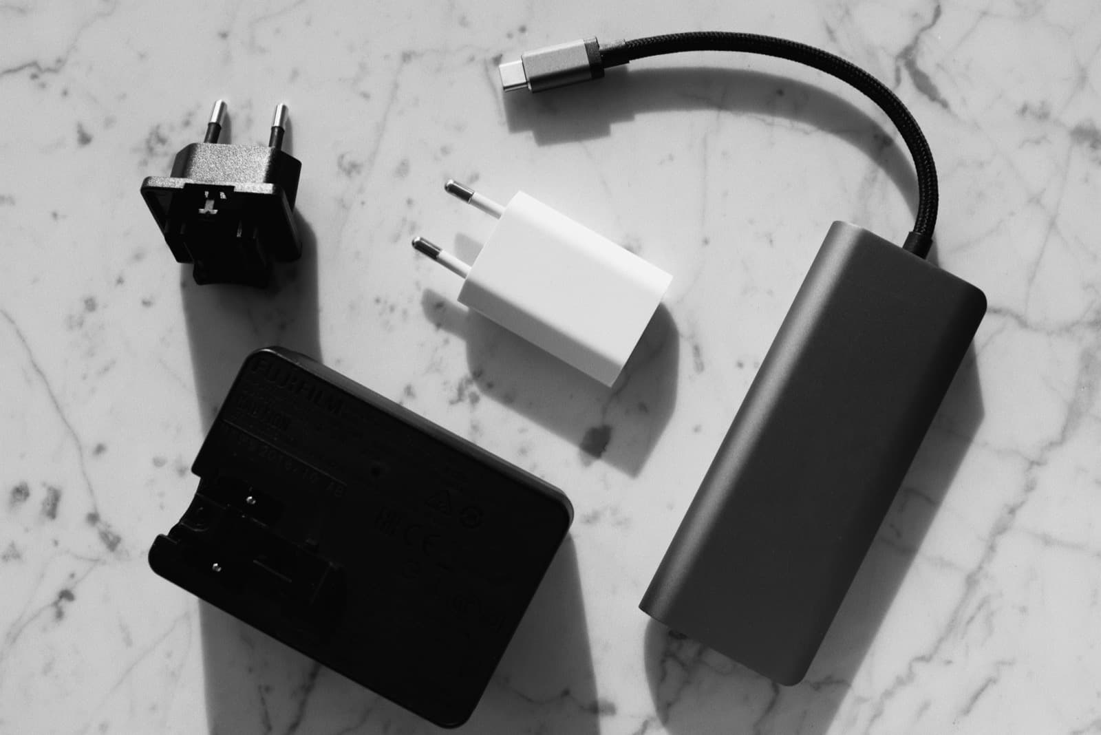 Chargers, adapters and a USB-C cable laid out in black and white