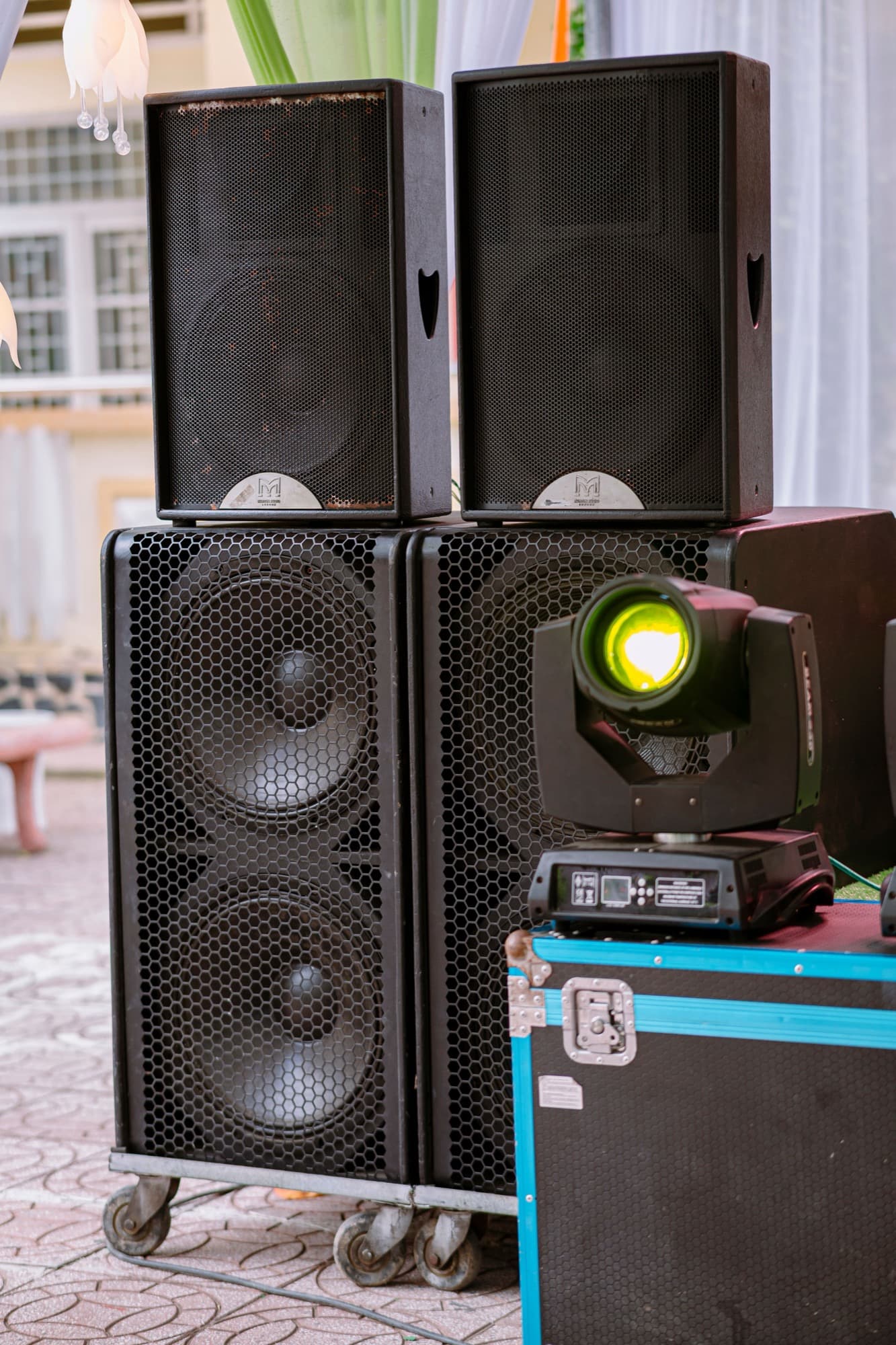 PA speakers and a moving-head stage light on event road cases