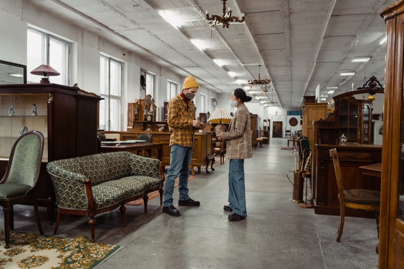 Two shoppers browsing antique furniture in a showroom