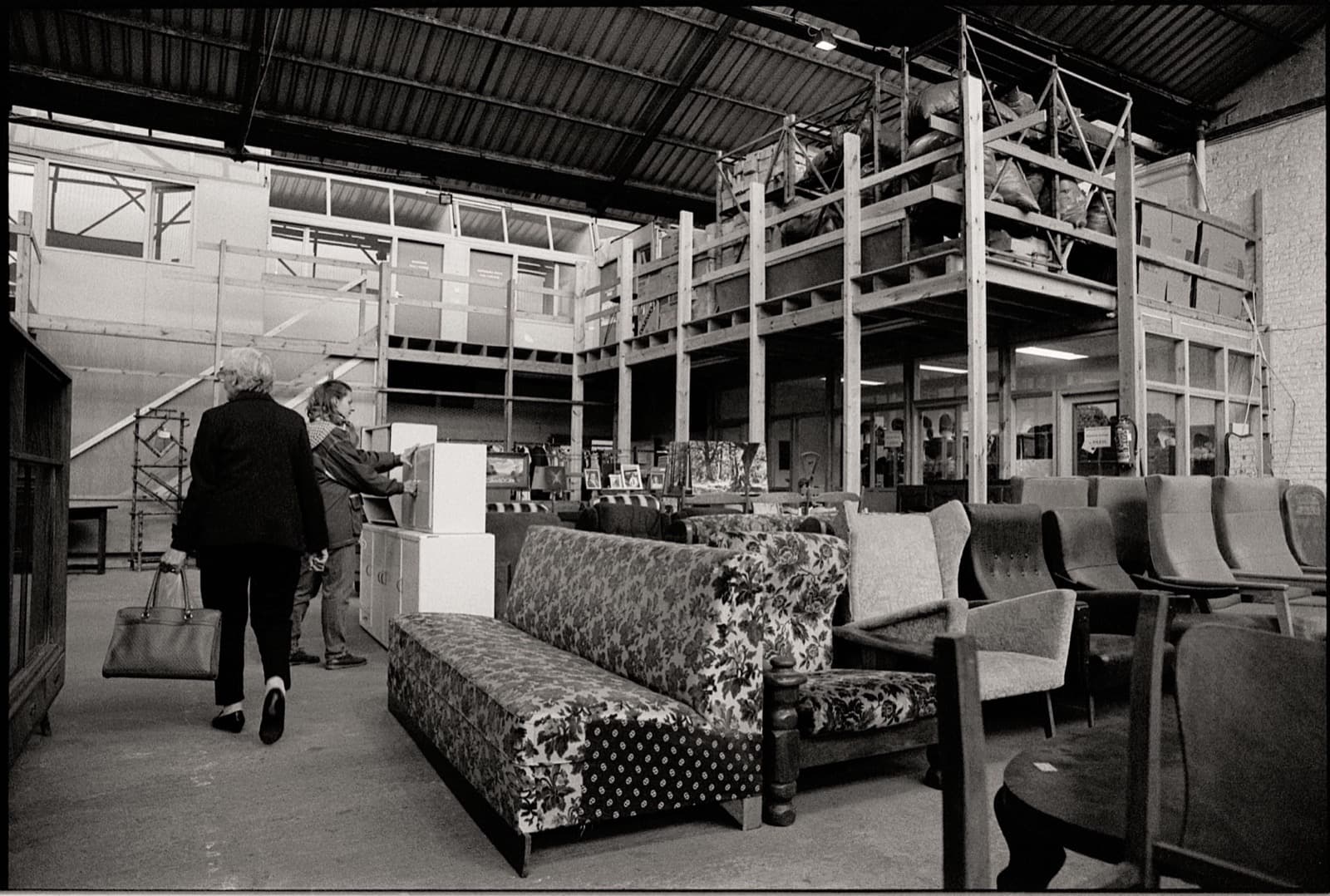 Shoppers browsing sofas and cabinets in a furniture warehouse